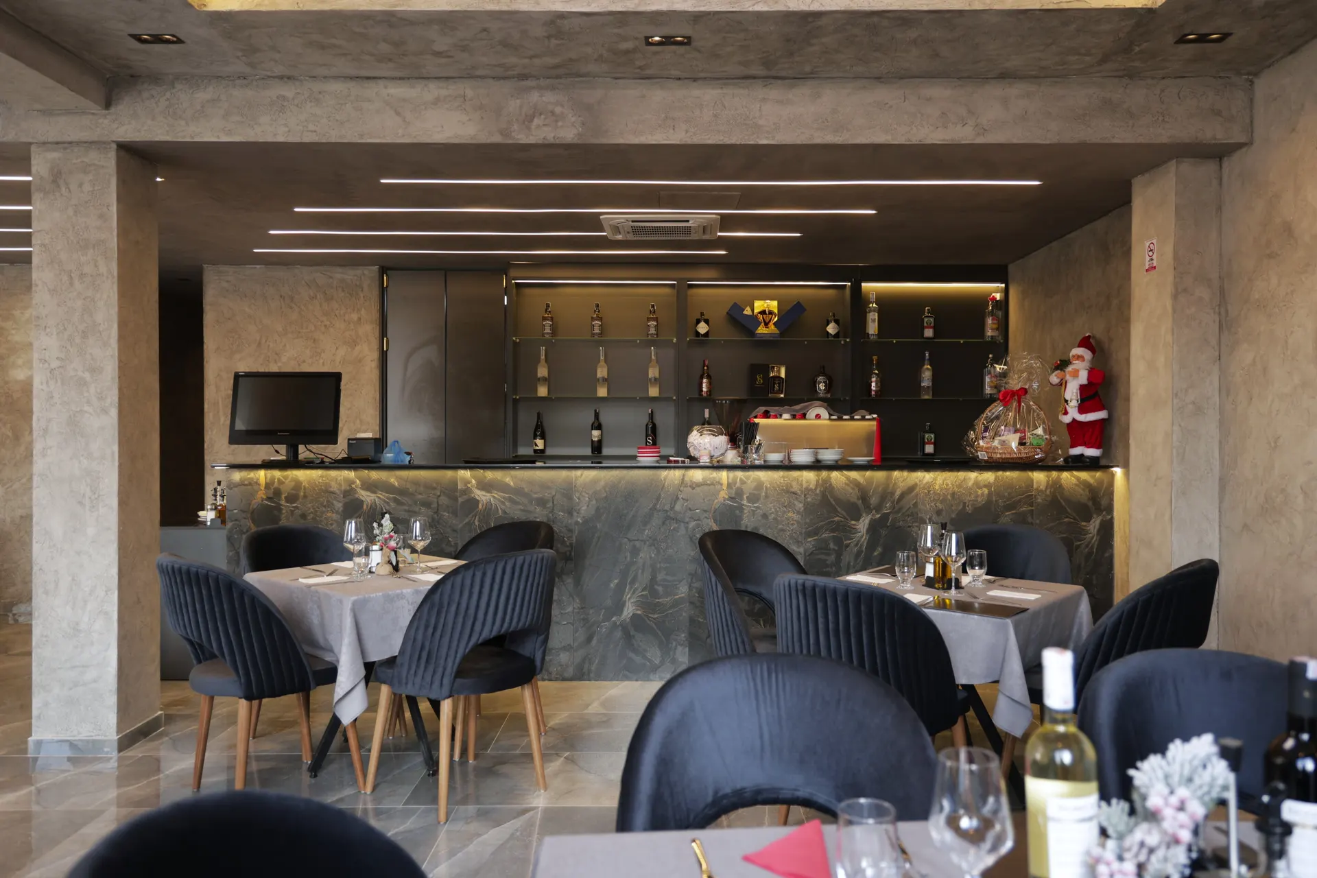 The hotel bar and lounge with dark chairs and a lit back bar