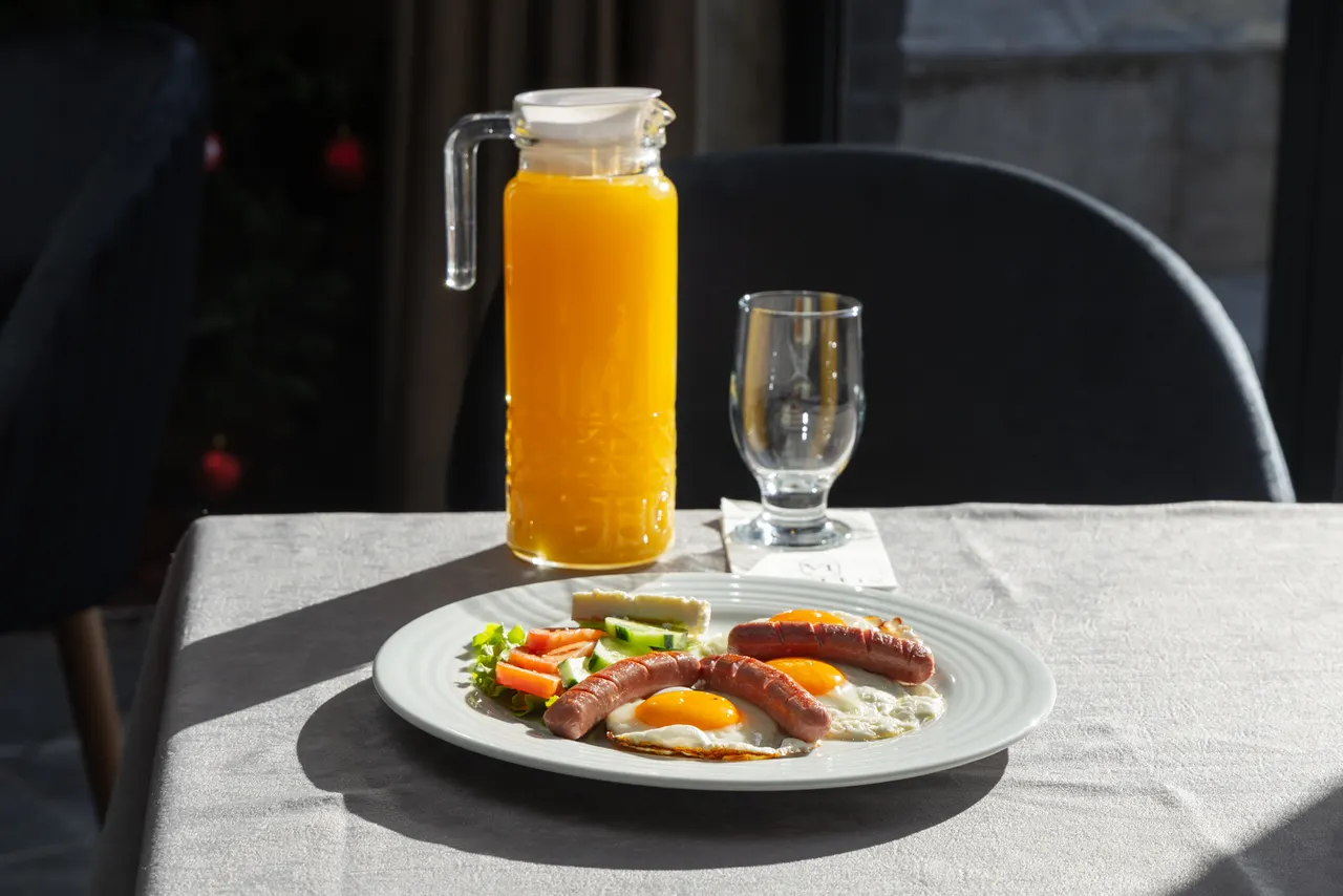 Breakfast plate with fried eggs, sausages and vegetables, orange juice