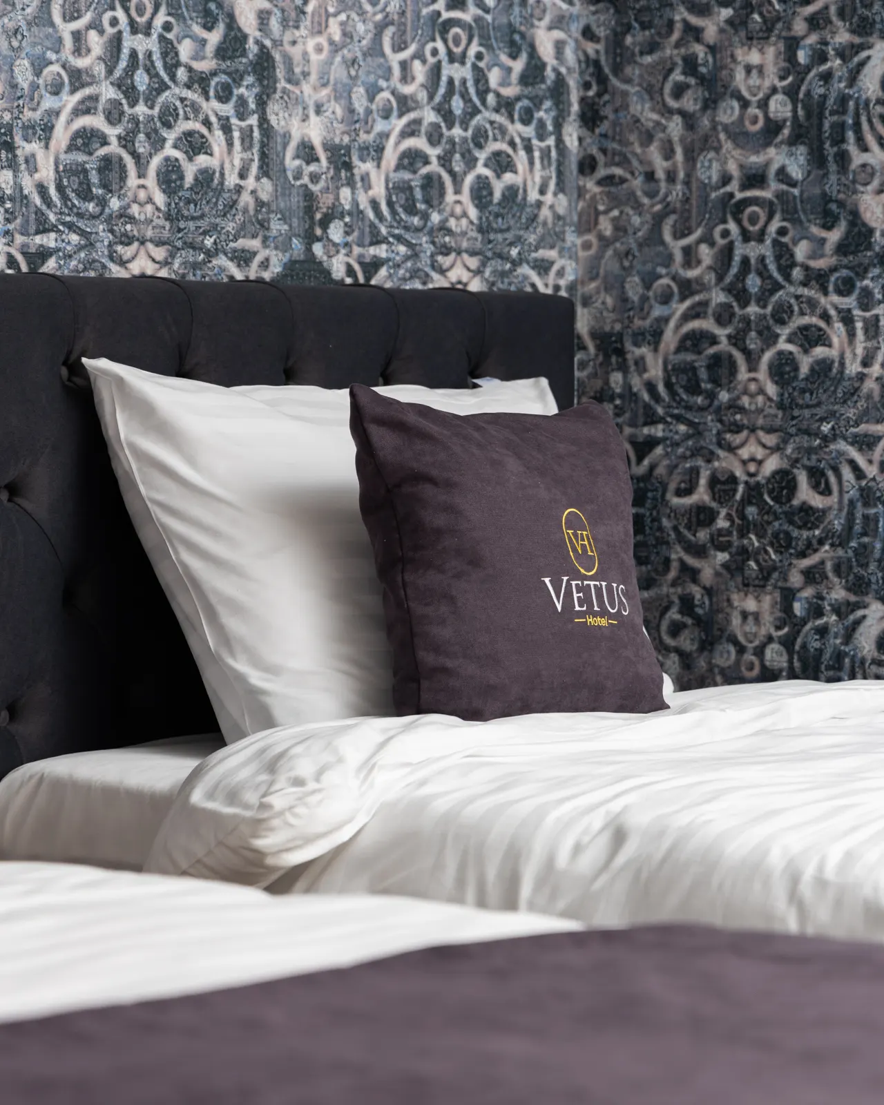 Vetus embroidered pillow on a white bed