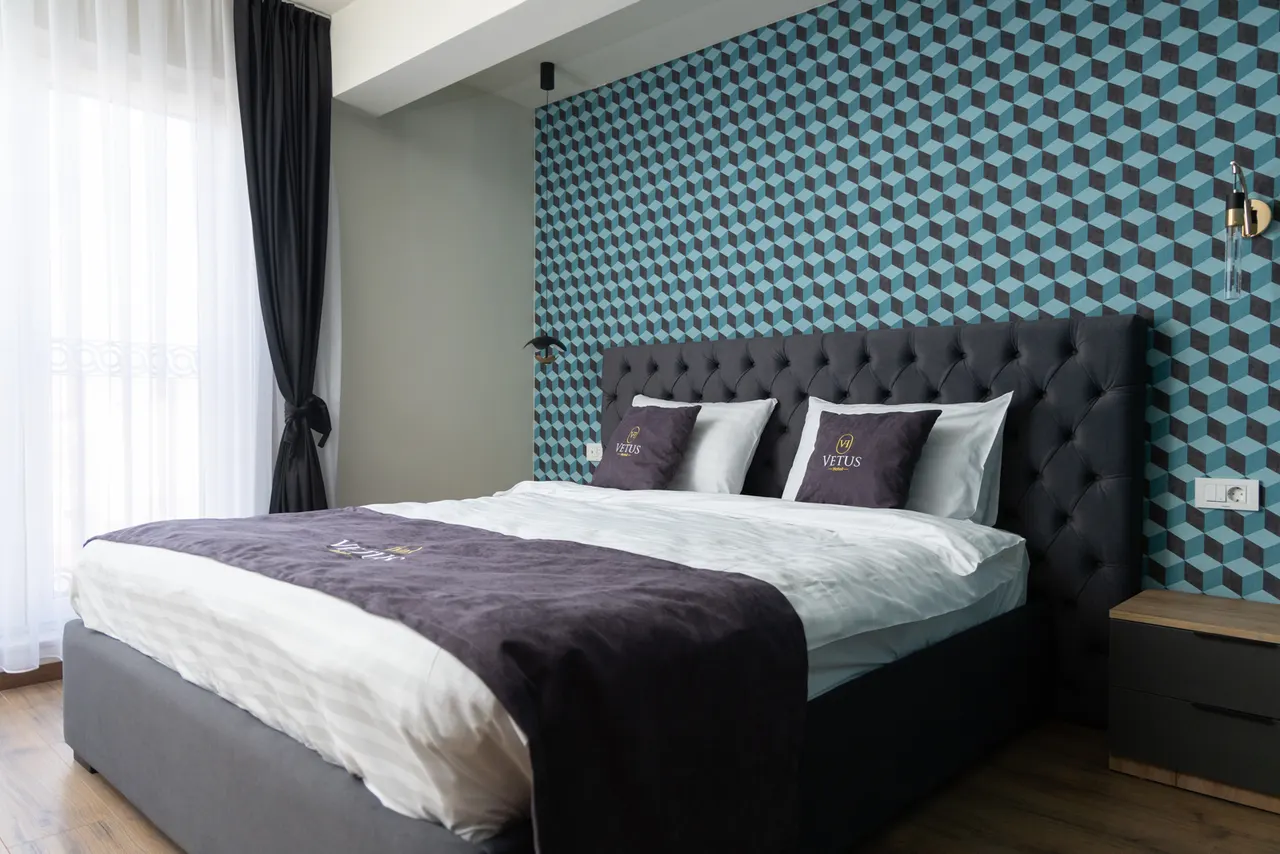 Luxury suite bedroom with a teal geometric wall and dark headboard